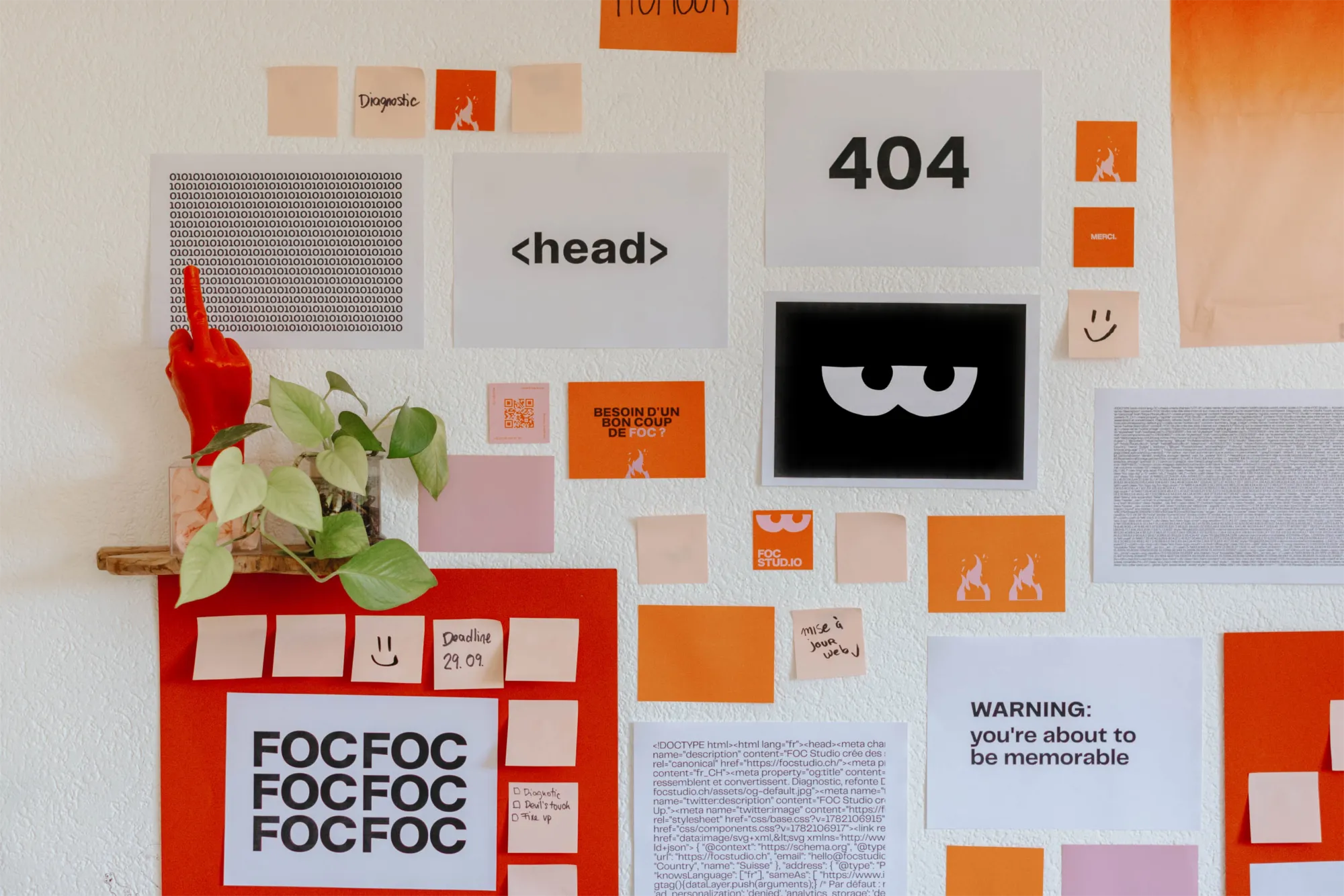 Le mur du studio FOC à Fribourg : affiches, post-its et la bougie doigt d'honneur signature